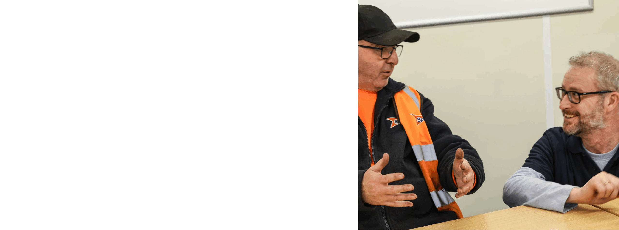 Two men talking, one wearing a hi-vis vest